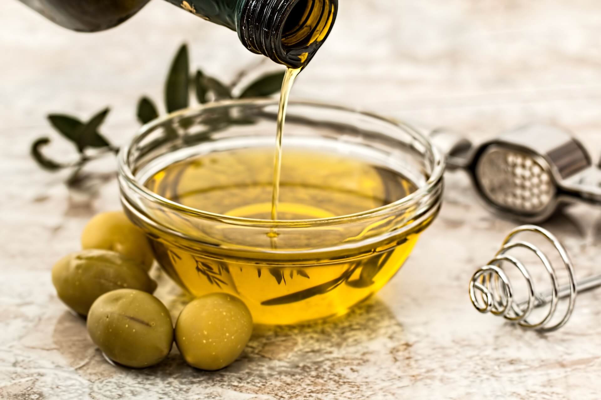 A person pouring olive oil into a small dish