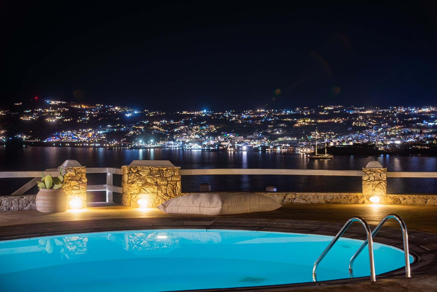 A pool and a city in the distance during the night