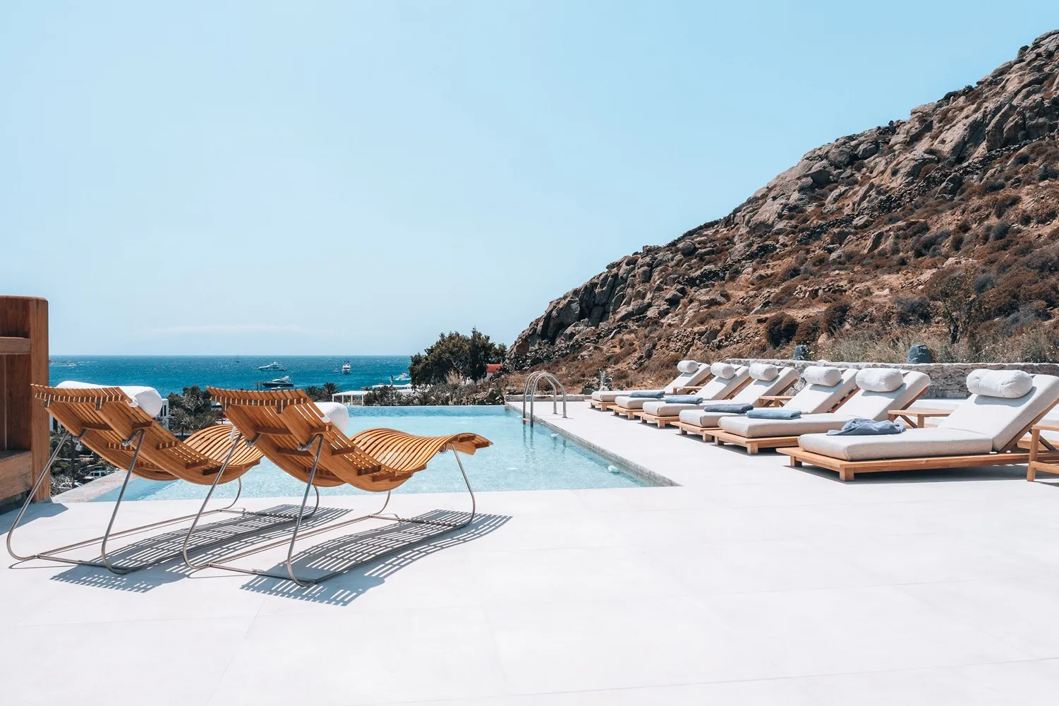 View of the pool with sunbeds around it and the sea in the distance 