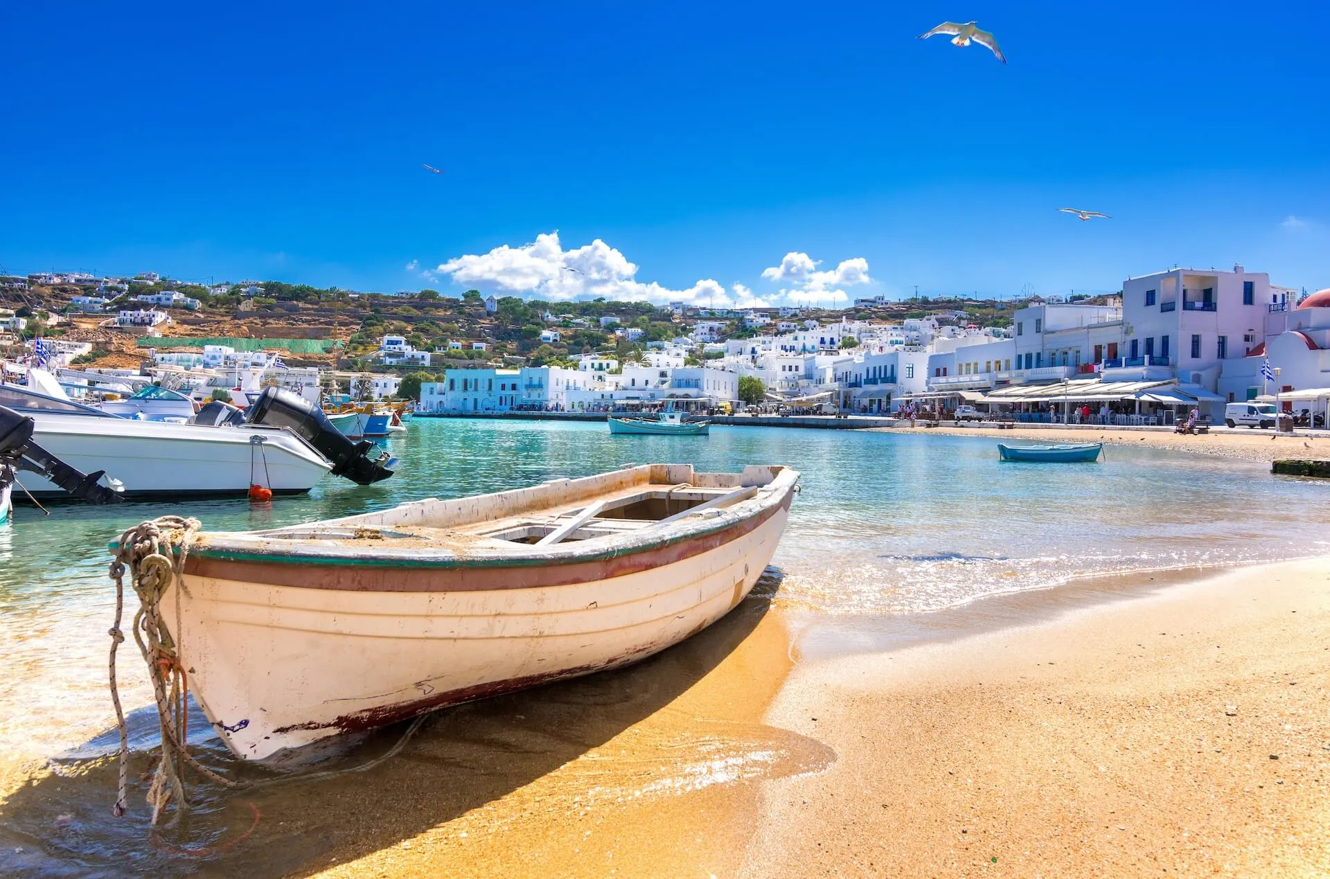 A view of an area filled with white buildings and houses, and a boat on the sand