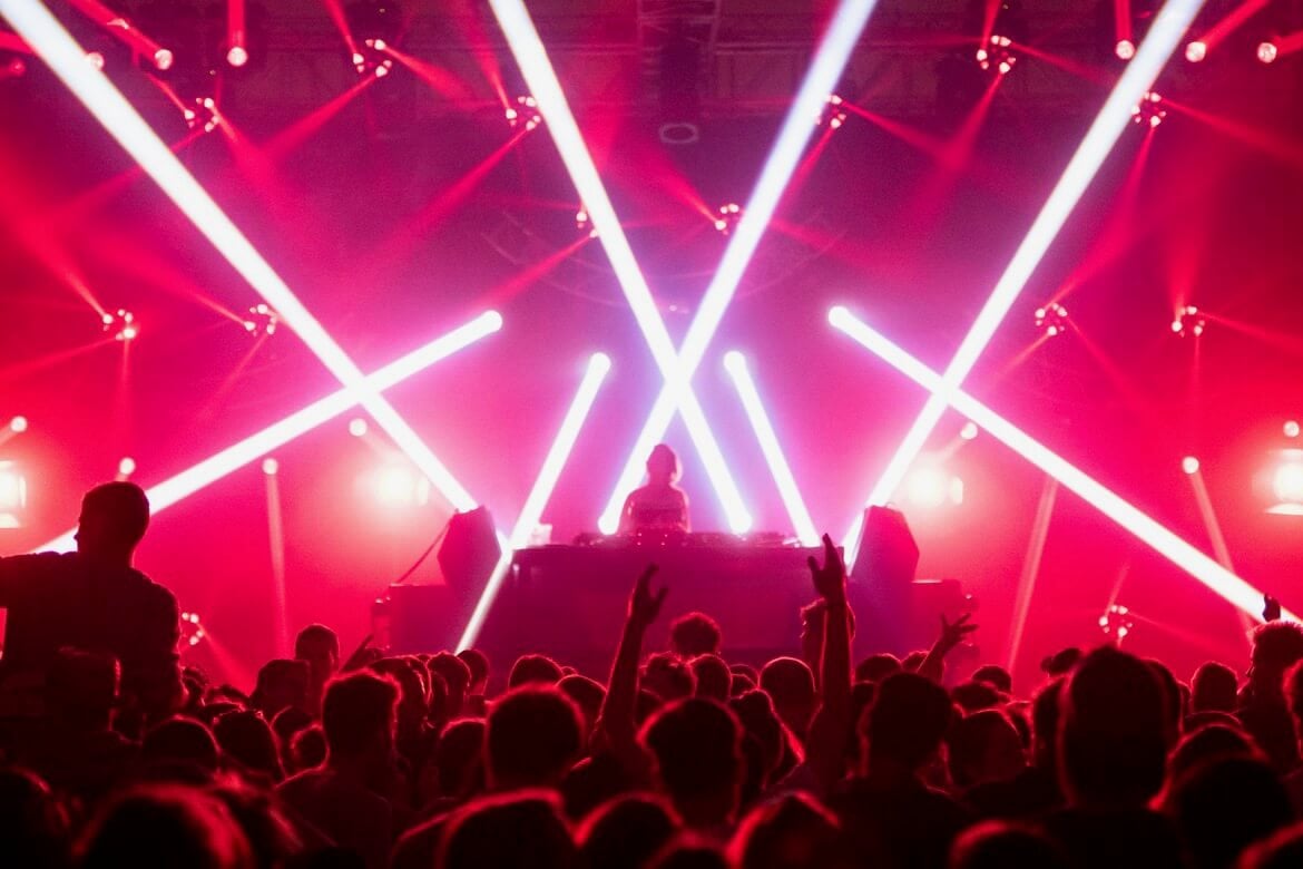 Crowd in the club, red lights, and a DJ on the stage