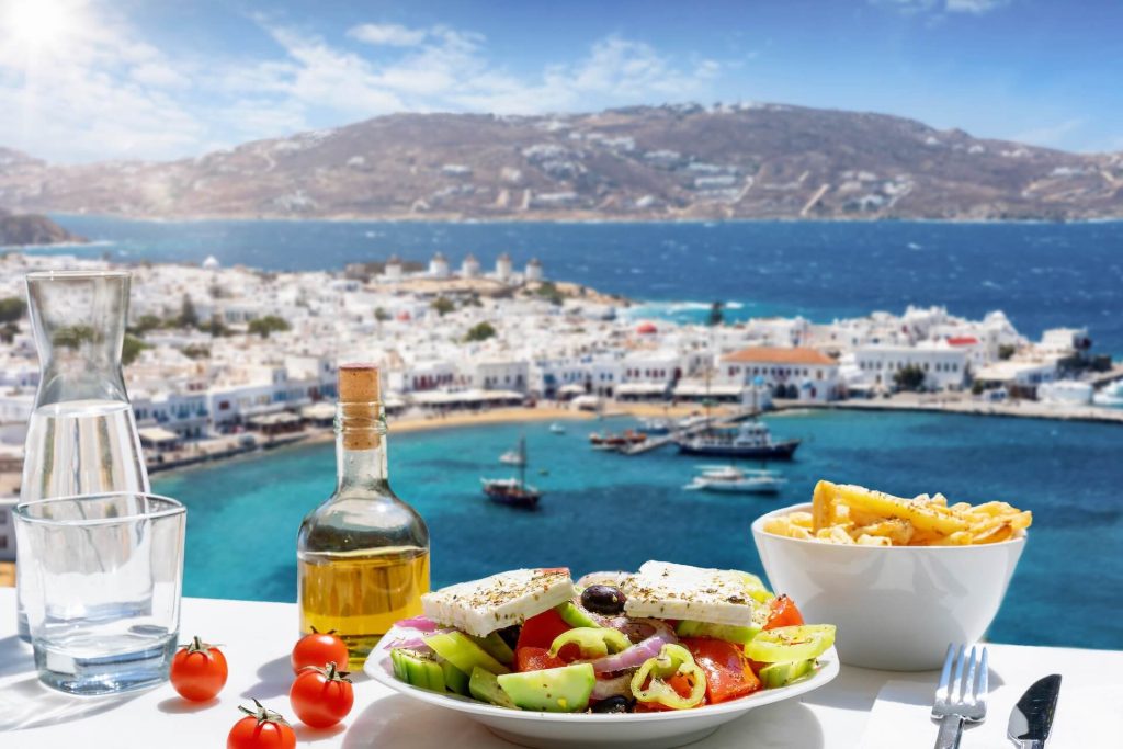 Greek salad, fries, and olive oil on the table overlooking the port in Mykonos