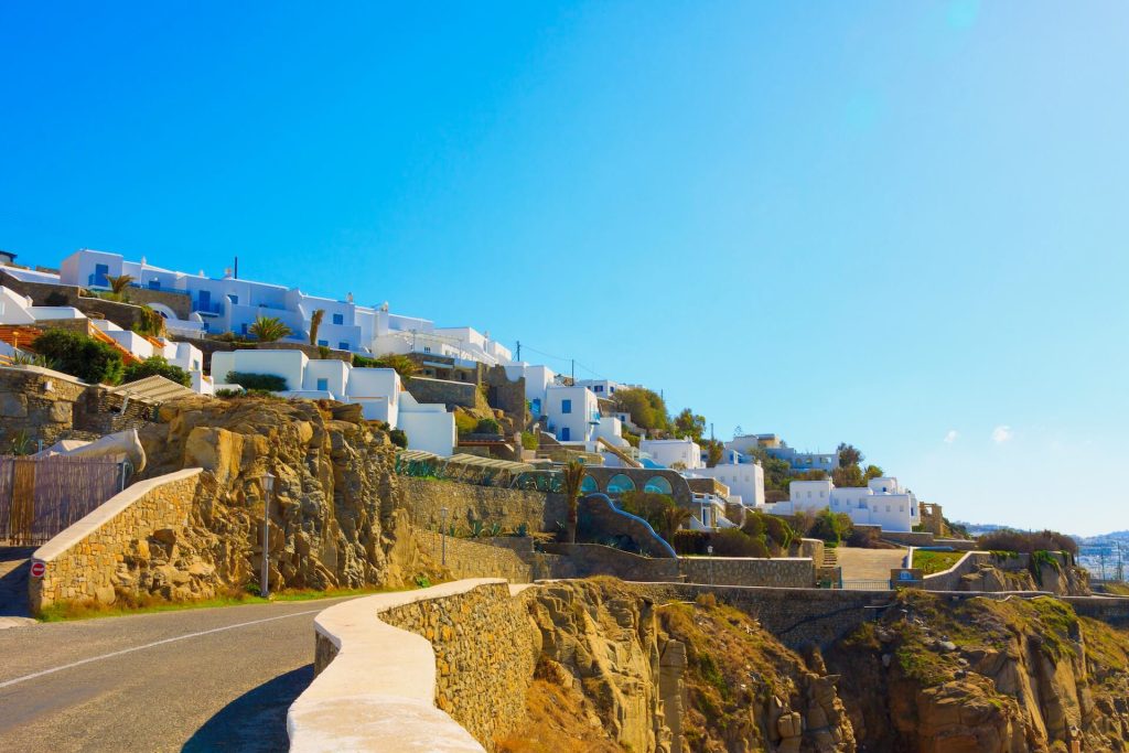 Road on the coast of Mykonos and white houses in the distance