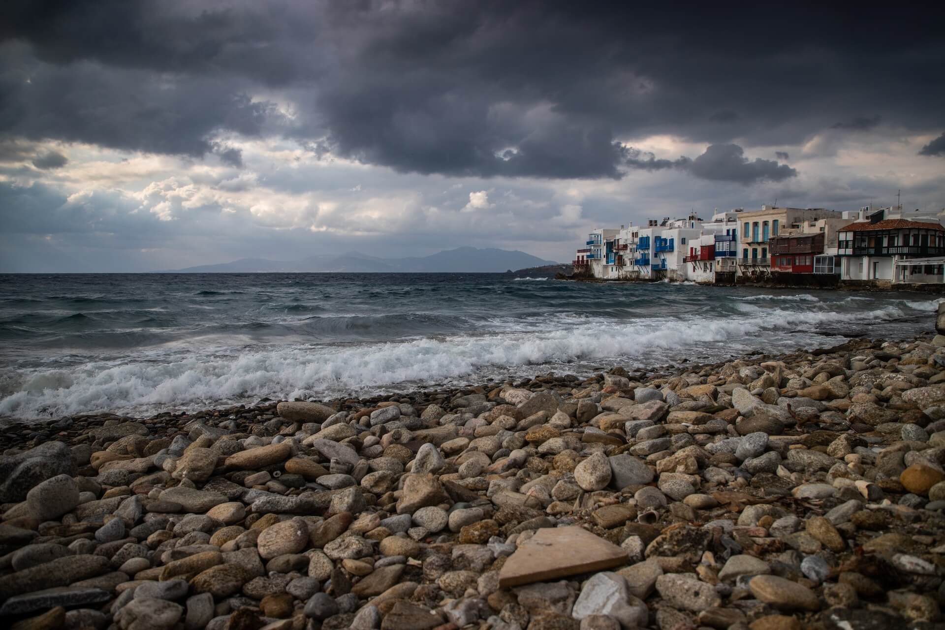 The coast of Mykonos in the winter, clouds, and houses in the distance