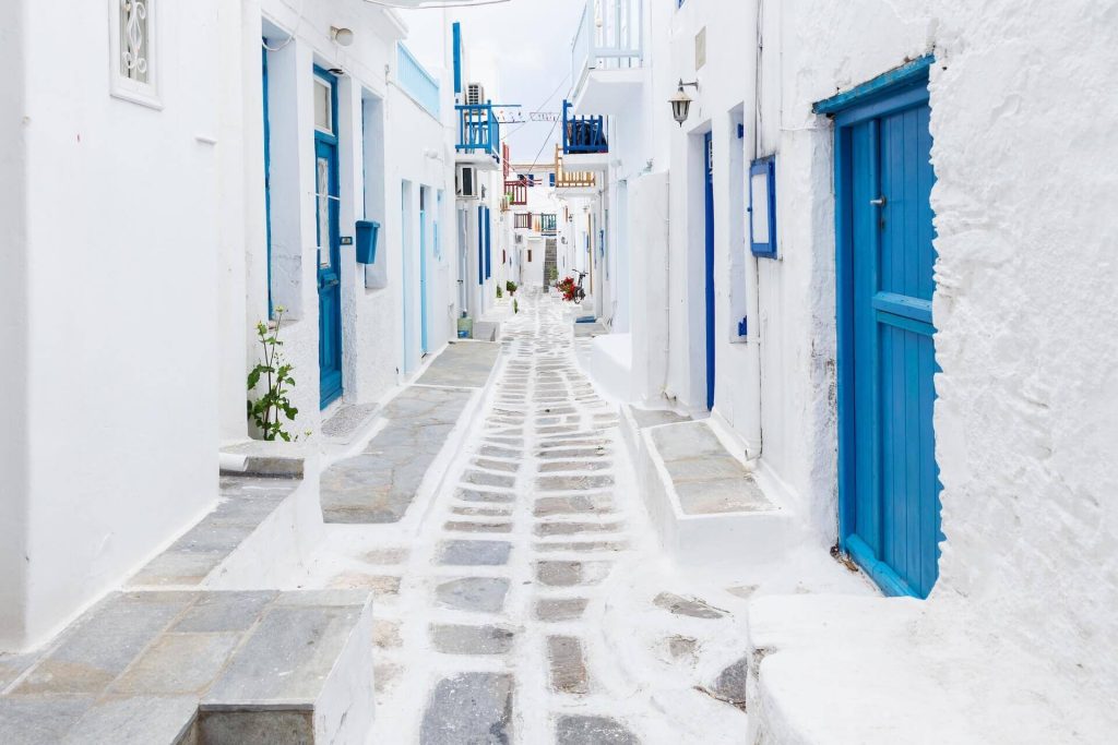 The view of the street in Chora, Mykonos, white houses with blue doors on both side