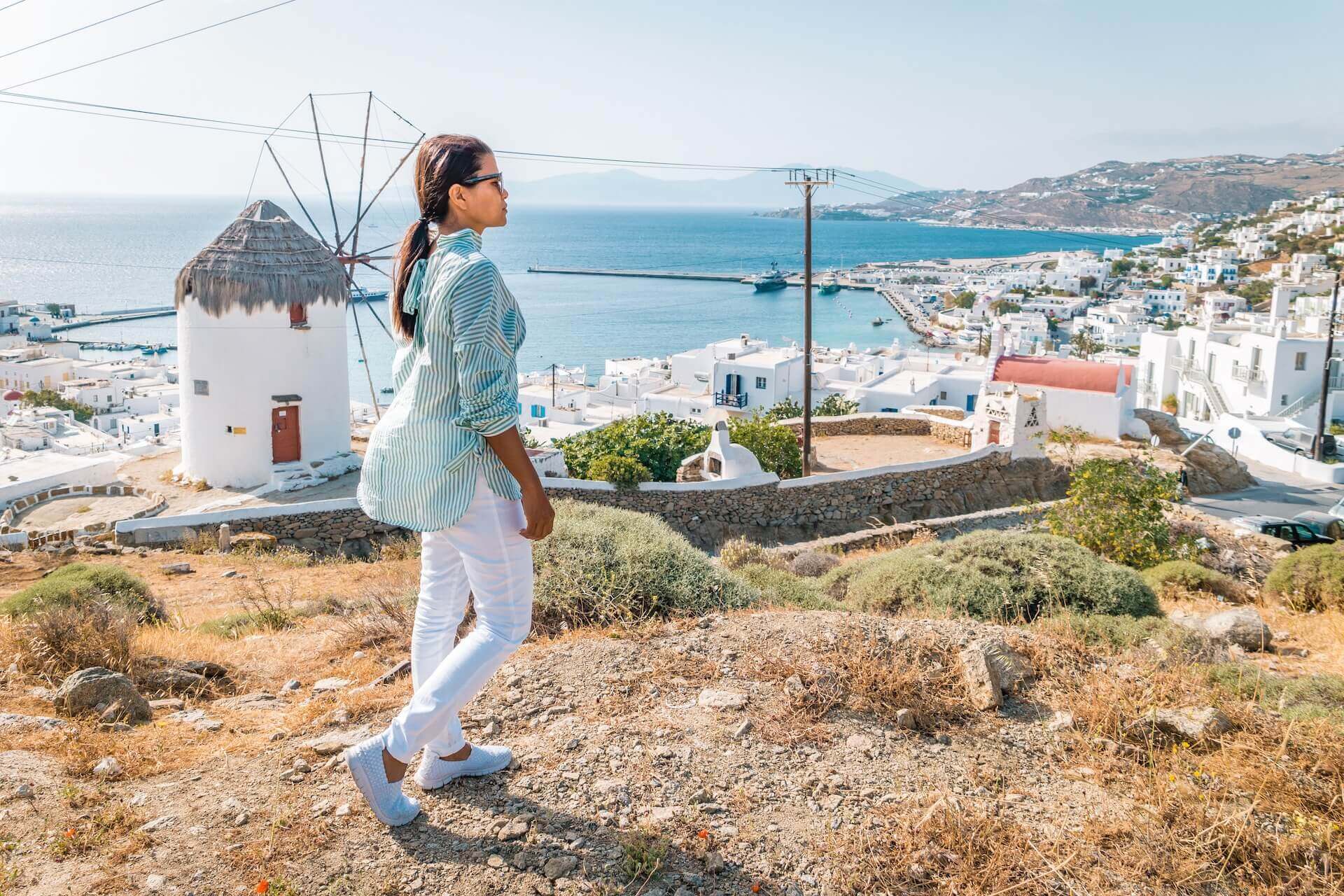 Woman in a blue shirt and white pants ready for weather in mykonos in november
