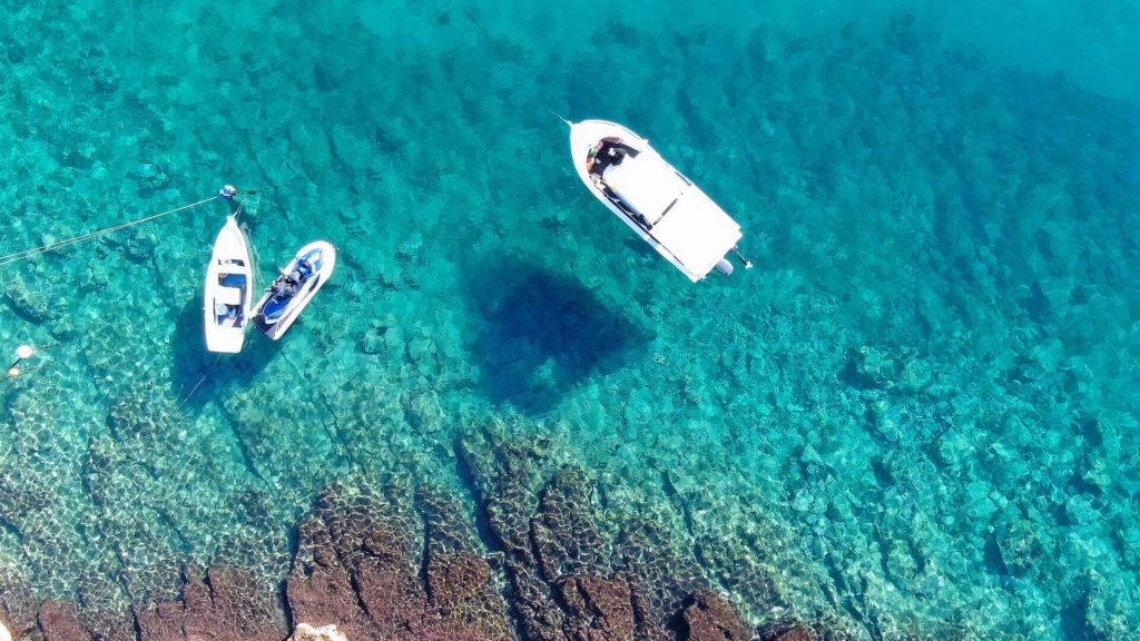 Two boats and a jet ski on the coast of Mykonos, photographed from the air