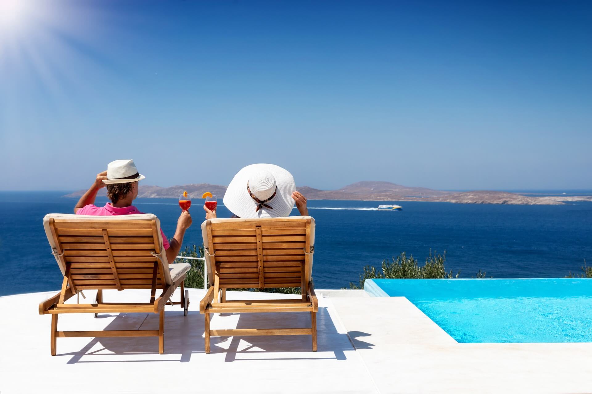 A couple relaxing in one of the private Mykonos villas looking over the beach