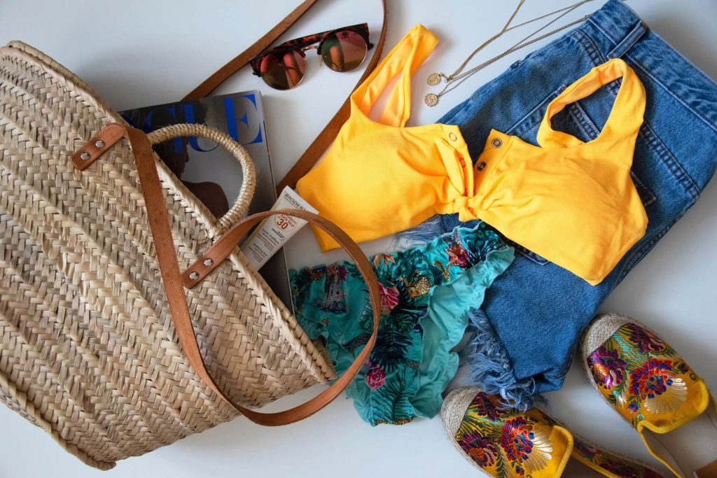Denim shorts, beach bag, Vogue magazine, sunglasses, swimming suit, and shoes