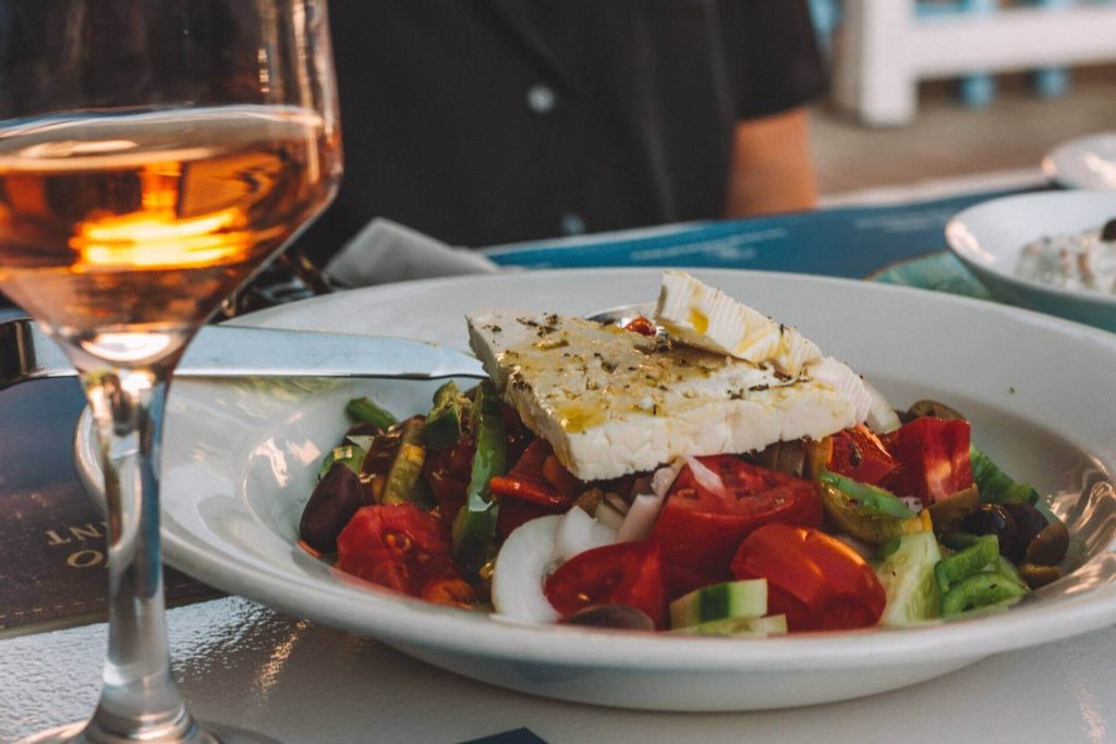 Greek salad and a glass of white wine on the table