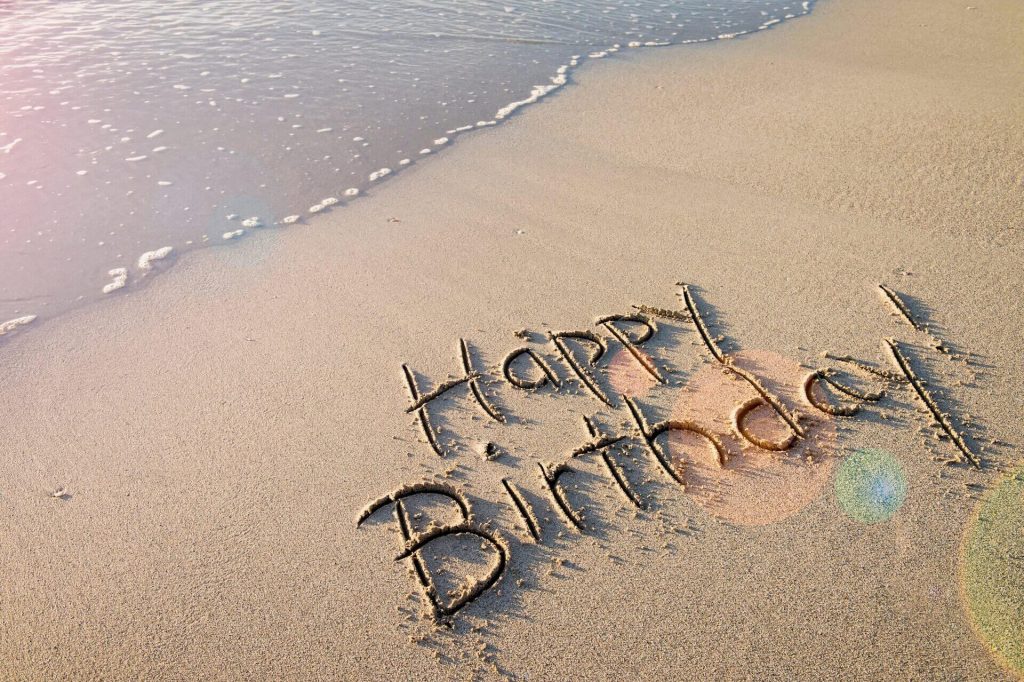 Happy birthday message written in the sand