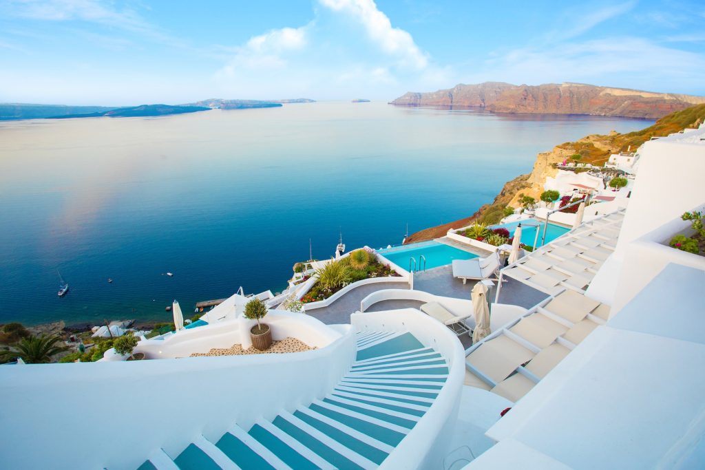 A view of white and blue stairs, small pools, and the Aegean Sea