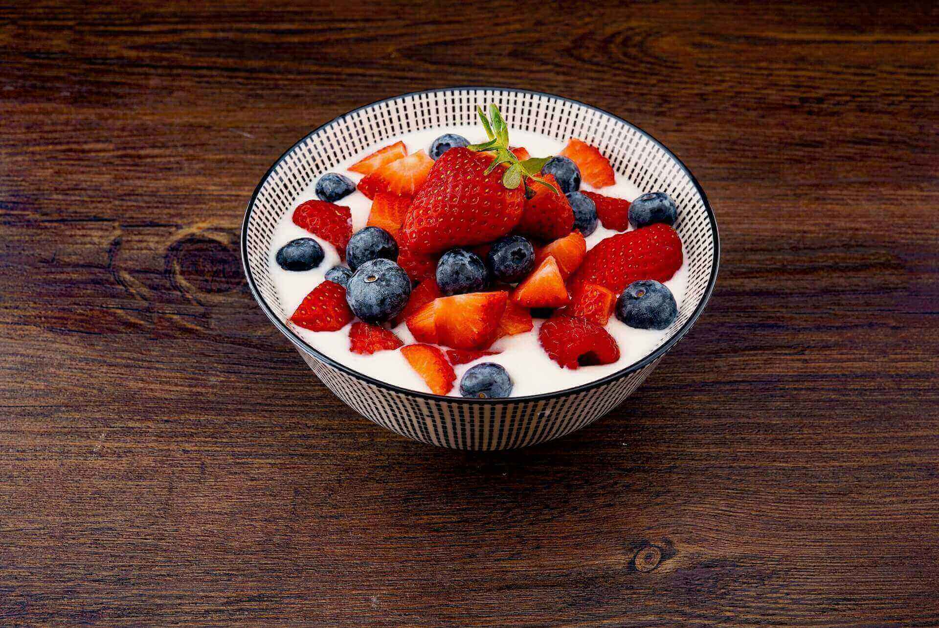 A bowl of yogurt with raspberries and strawberries