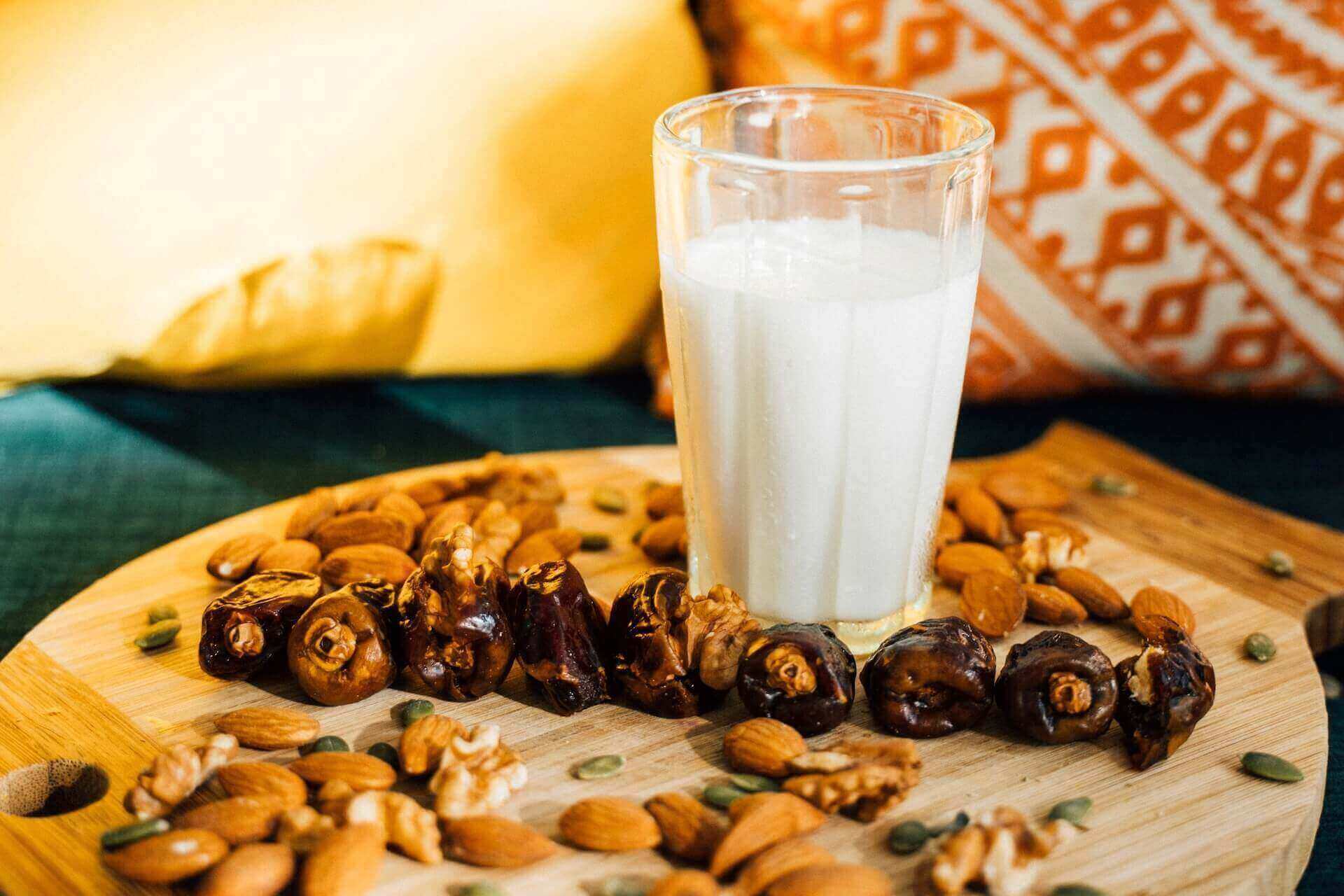 A glass of soumada on a board with some fruit and nuts