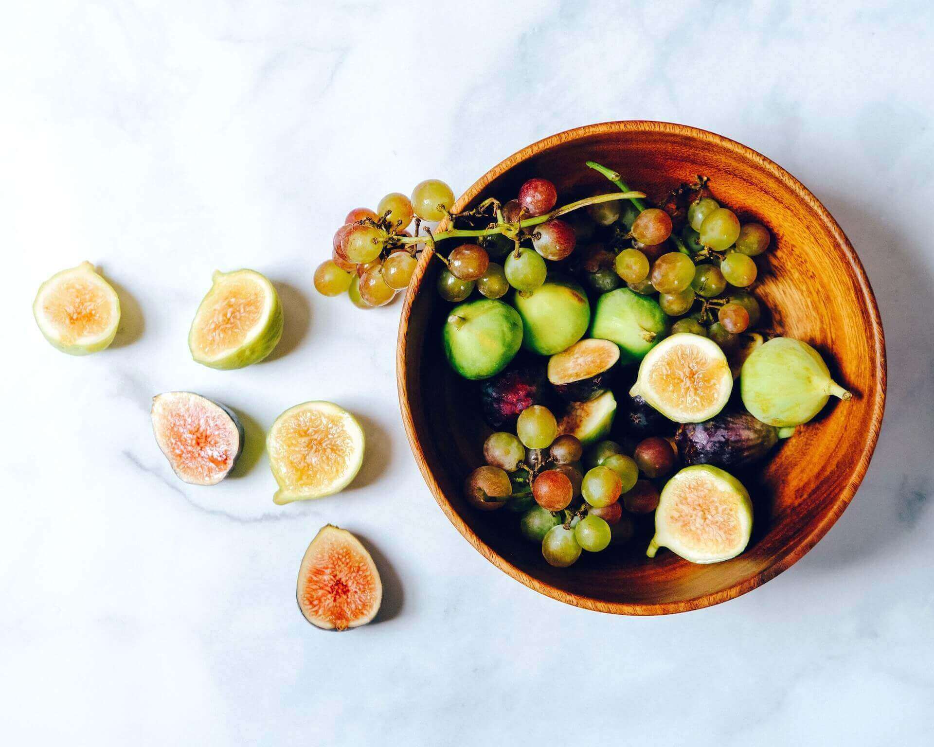 A bowl of figs and grapes on a marble surface