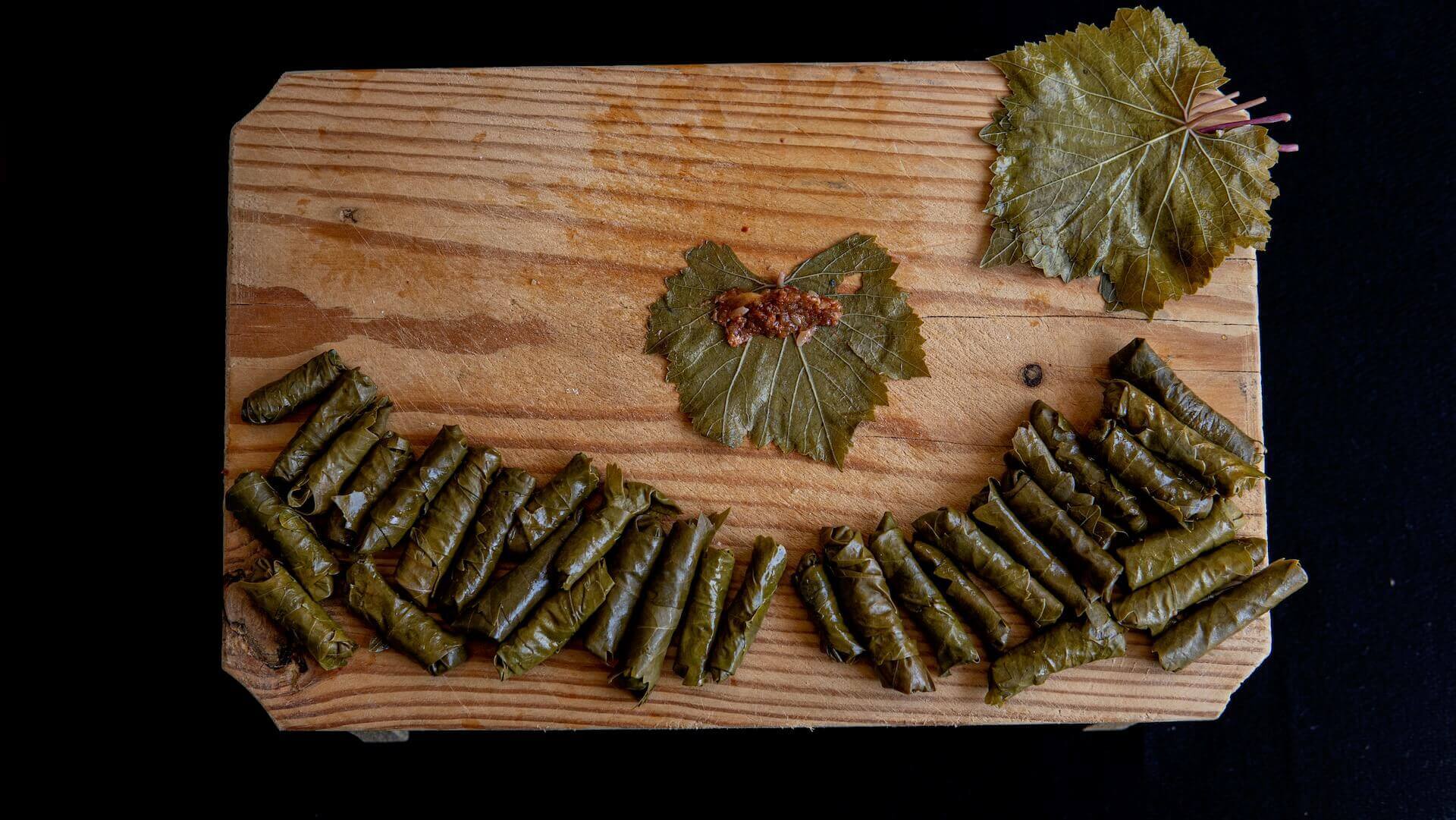 Many rolls of stuffed vine leaves on a wooden board