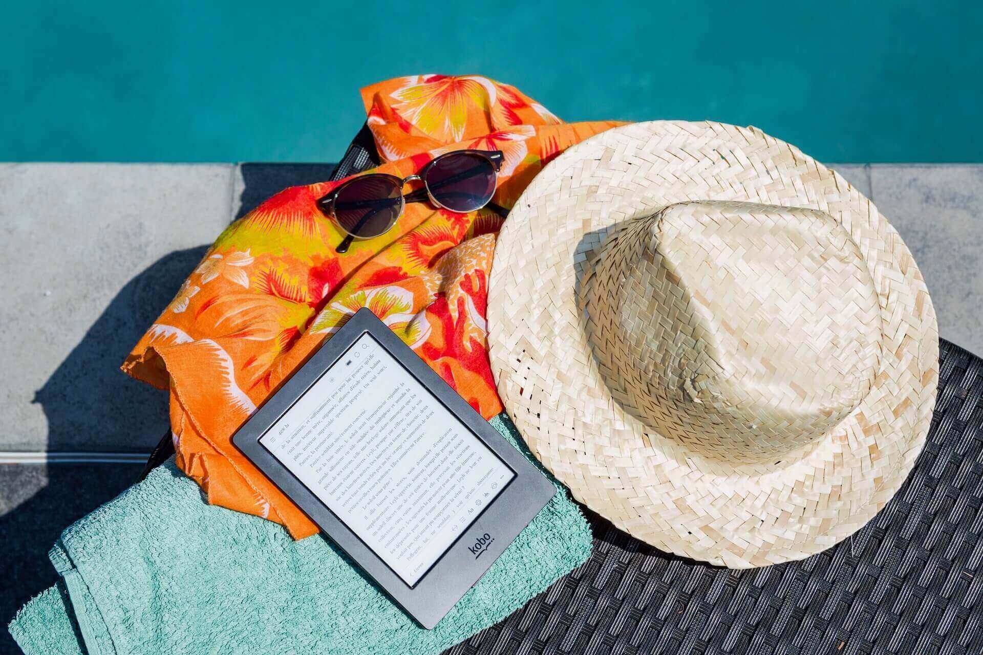 Kindle, a hat, and sunglasses on towels