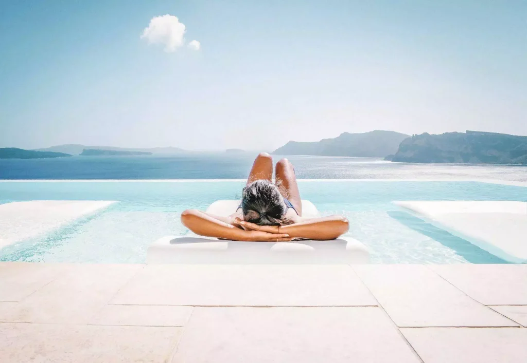 Woman lying on a sunbed in front of a pool of a luxury Mykonos villa