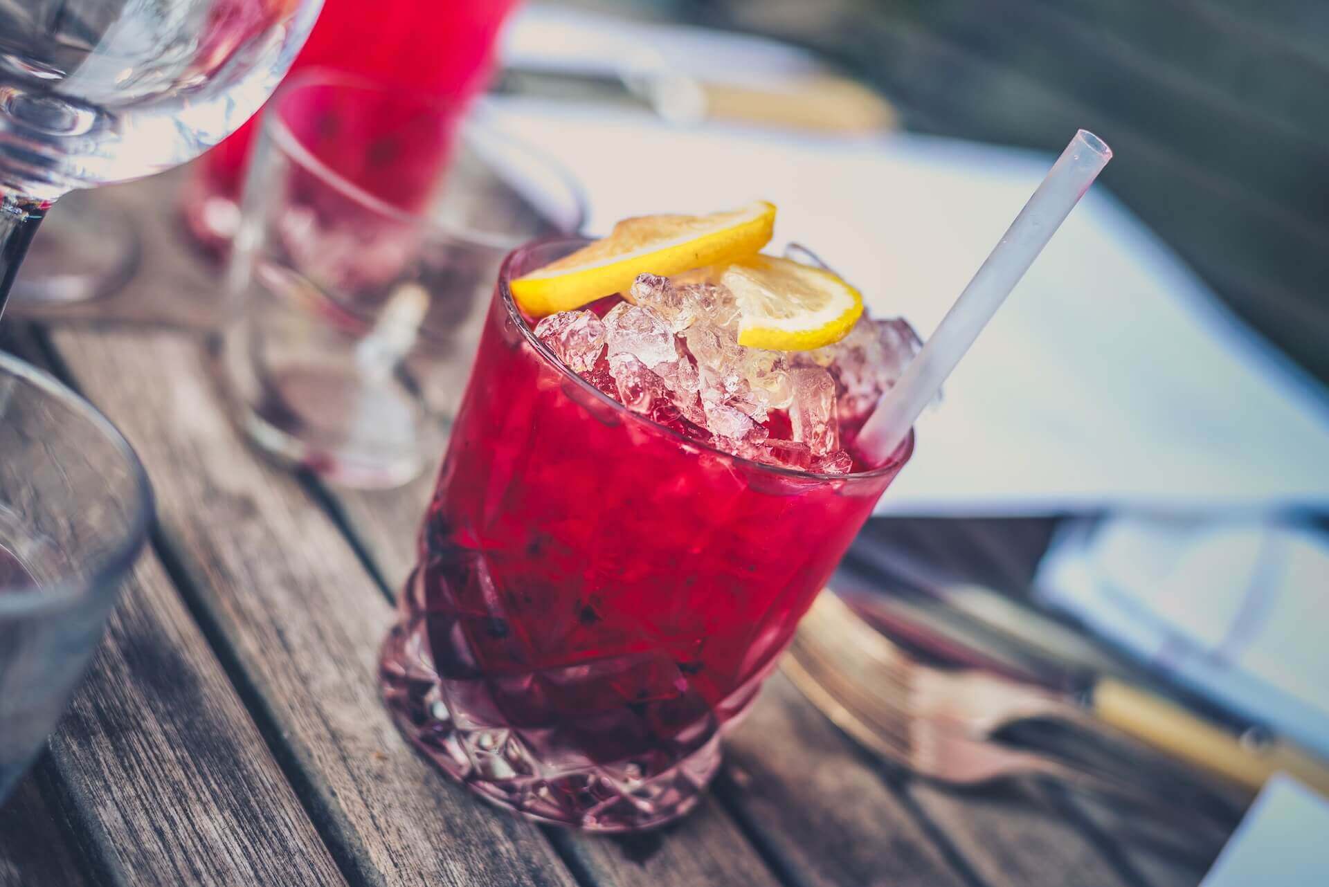 Red cocktail in a glass with some lemon and ice