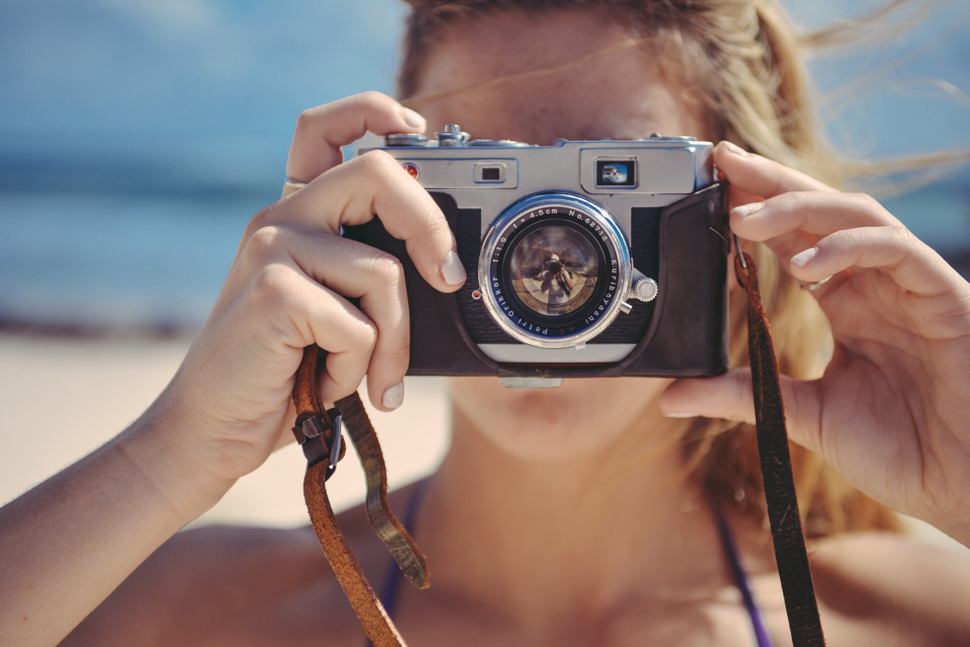 Girl holding up a camera at the beach