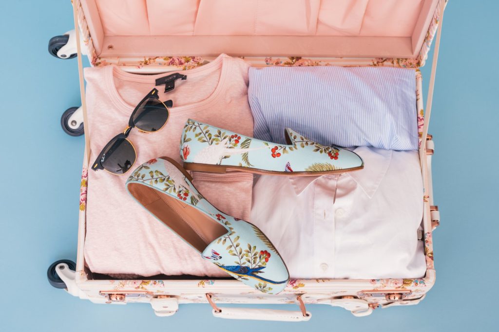 Clothes, shoes, and sunglasses in a suitcase