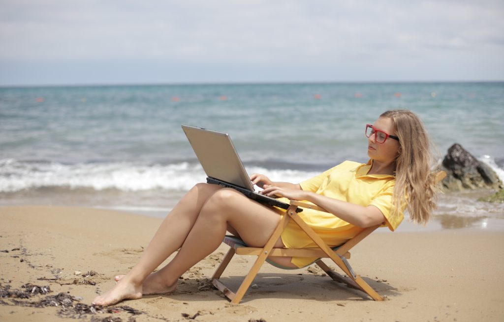 Girl working on her laptop at the beach on Mykonos