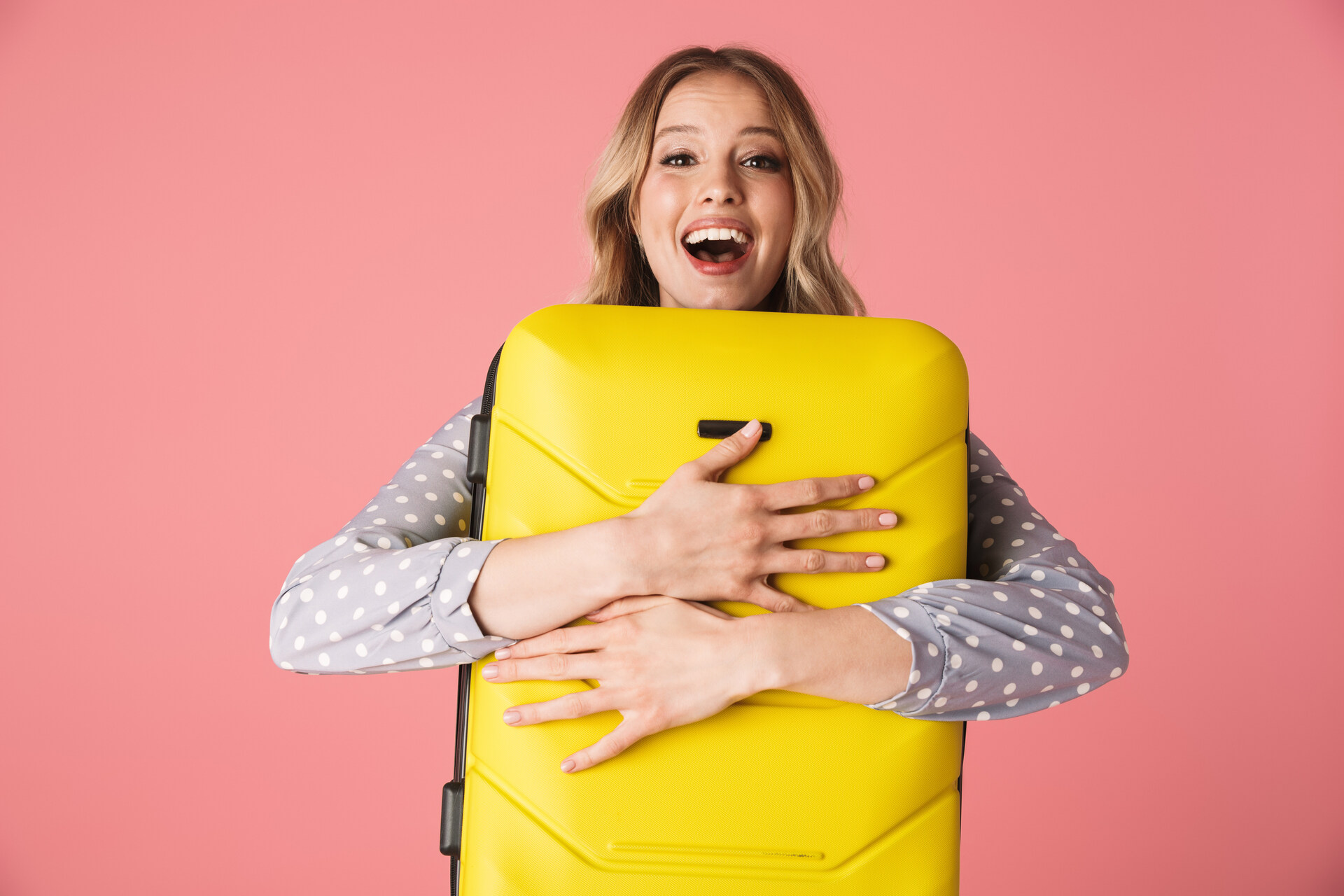 Woman hugging a yellow suitcase