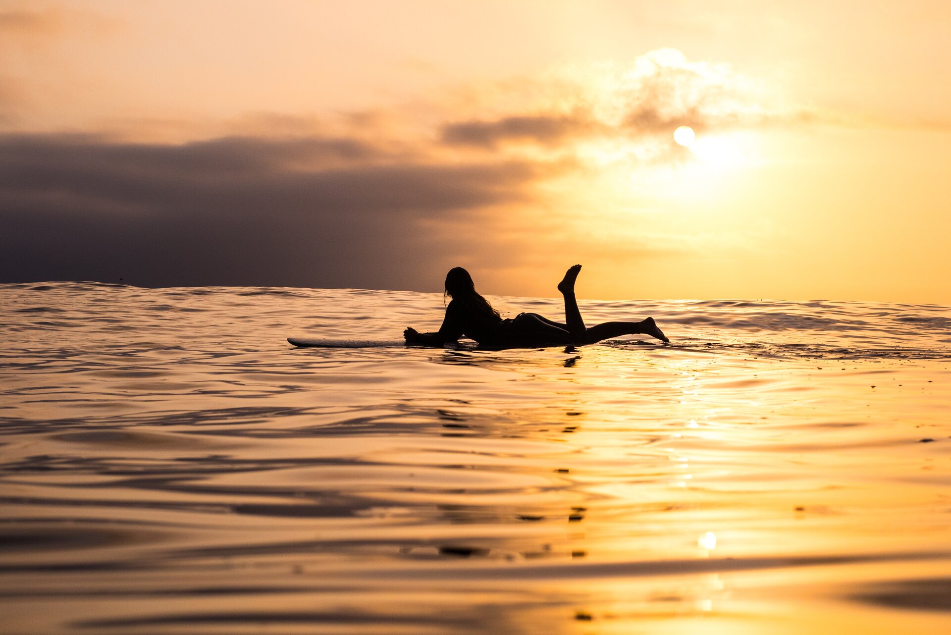 Woman lying on a surfboard in the sea