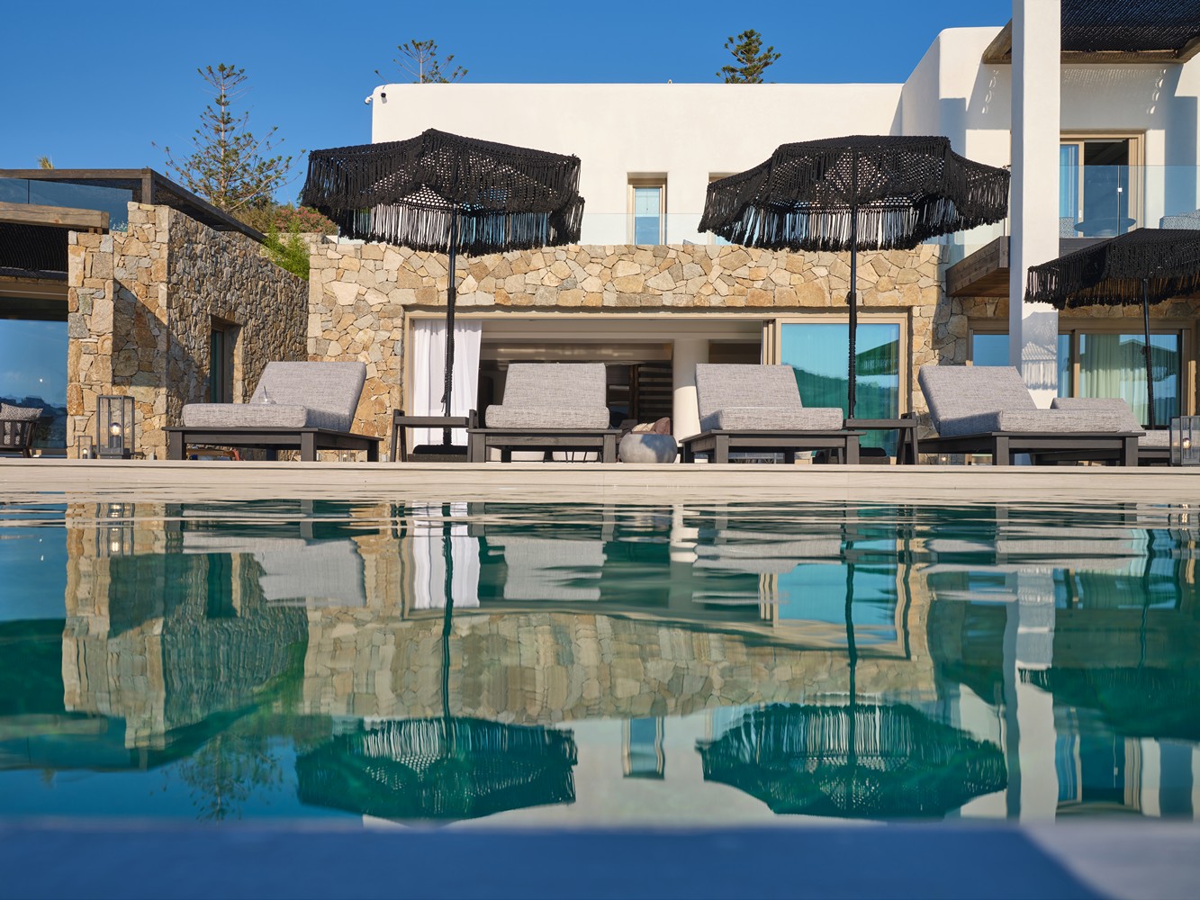 Sunbeds and parasols in front of a pool of one of the private villas in Mykonos