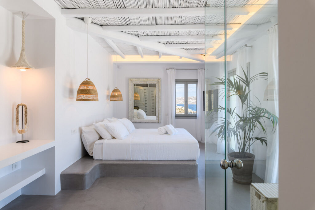 A modern white bedroom with minimalistic design, clean lines, and a comfortable looking bed. The room is well-lit and has a fresh, crisp atmosphere.