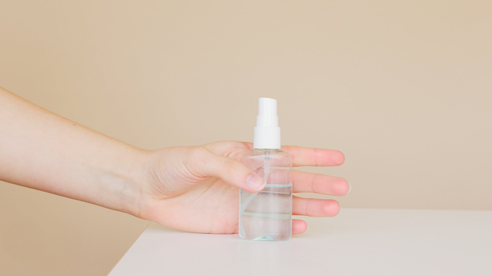 A hand grabbing a small plastic bottle