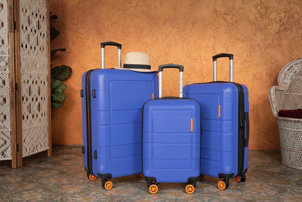 Three blue suitcases with a hat on one