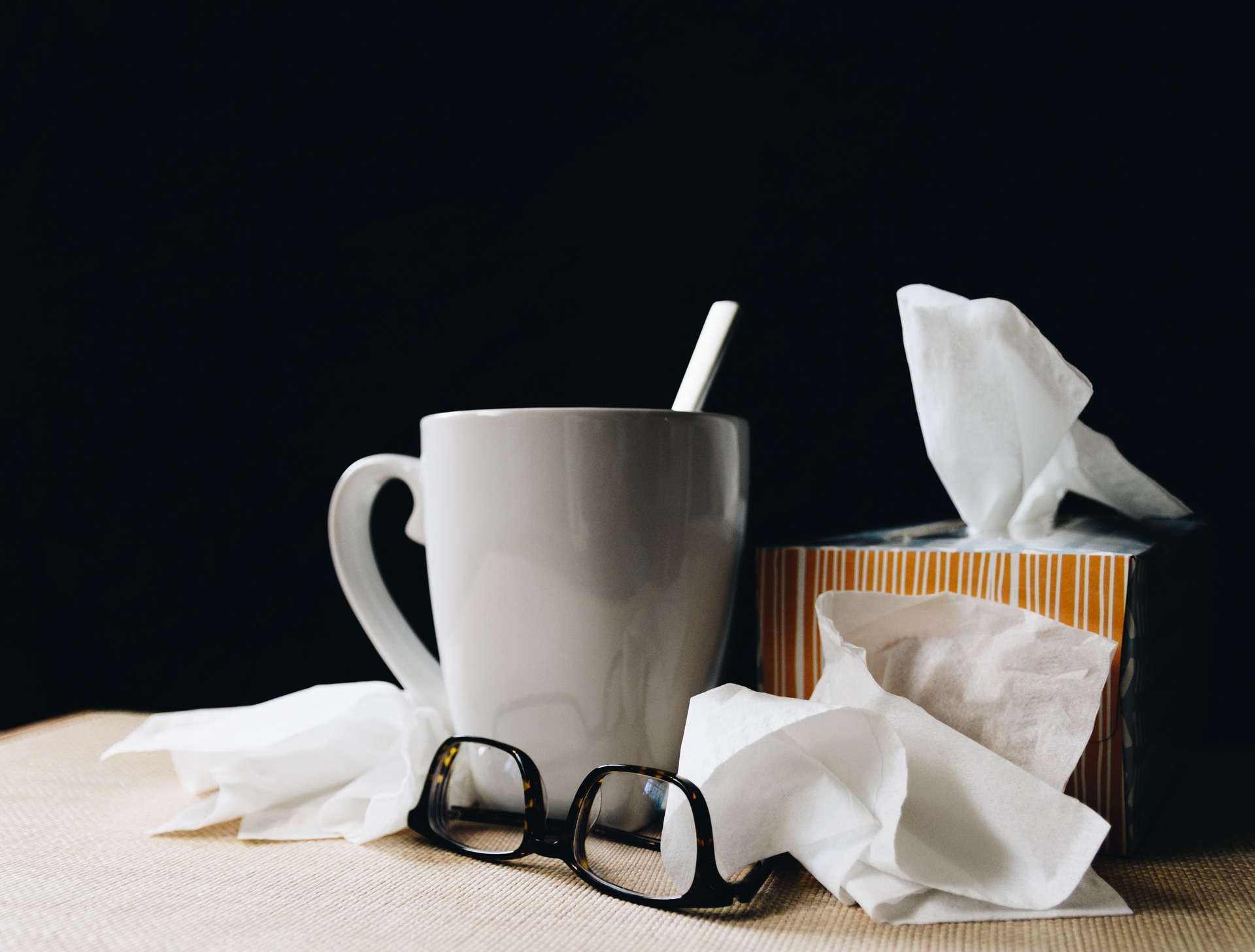 A mug, glasses, and tissues on a table