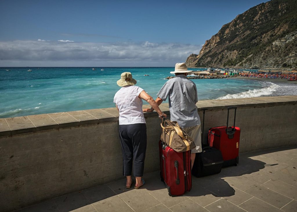 Couple standing by the sea with suitcases