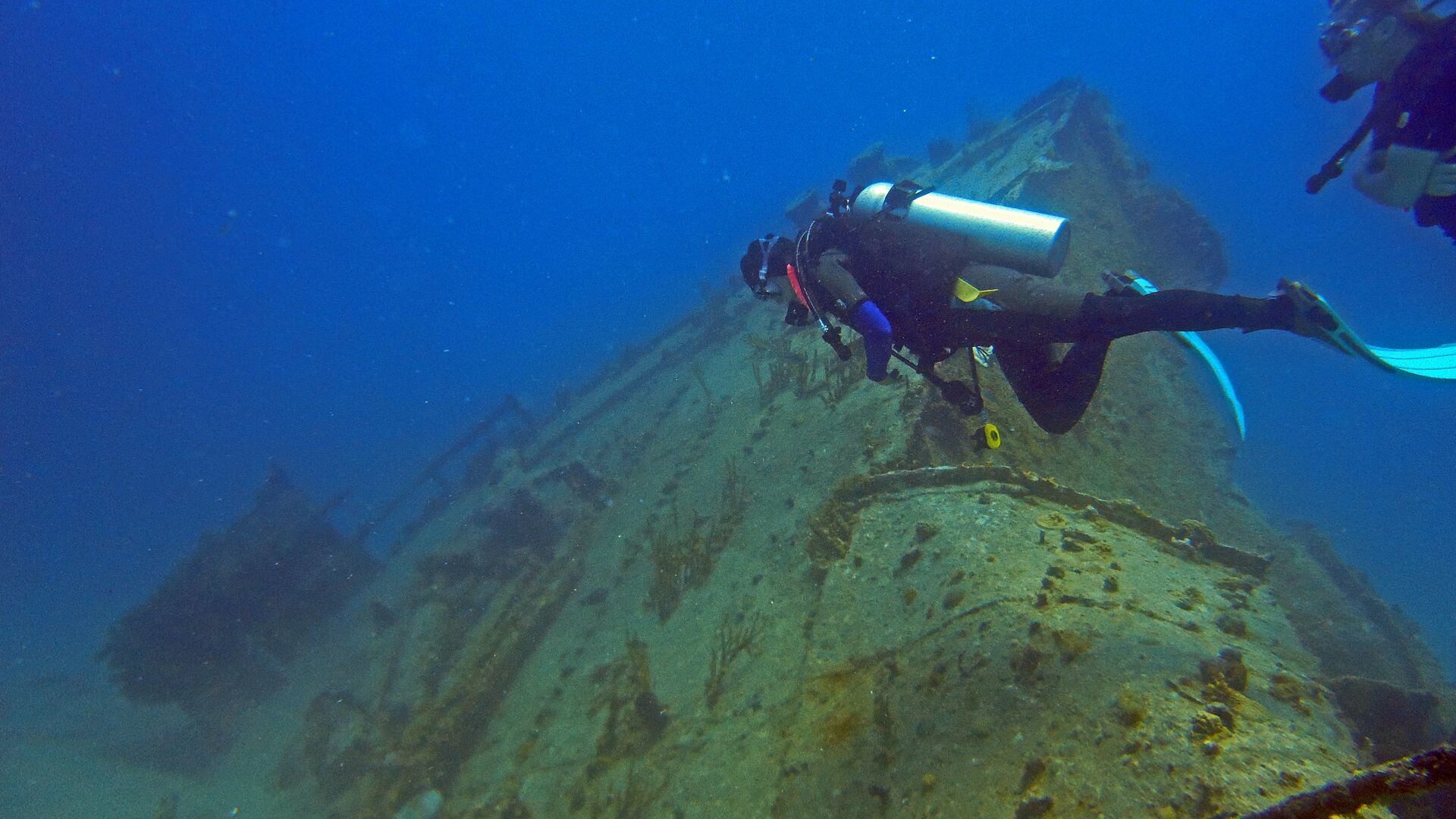 Diver in the water next to an old ship