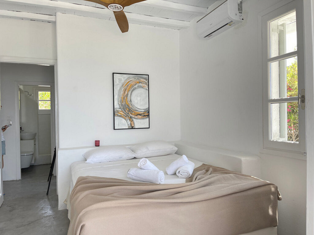 Cozy bed, big windows, and white walls. Mykonos lavish villa for rent.