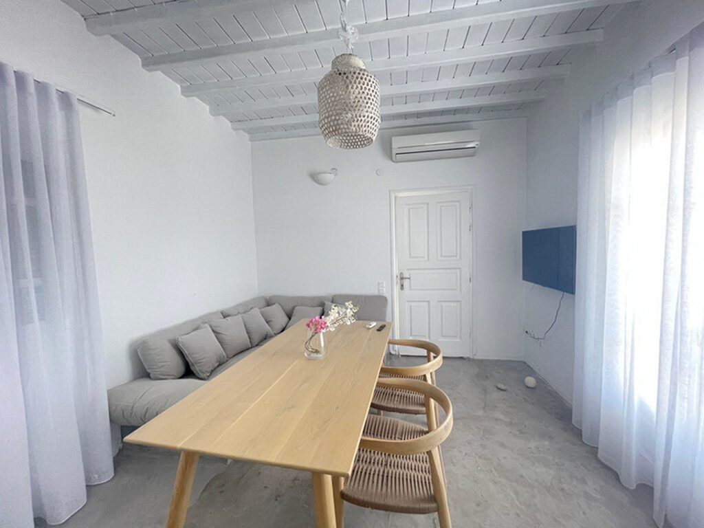 Sofa, table, and a TV in the dining room in Mykonos' best private home for rent.