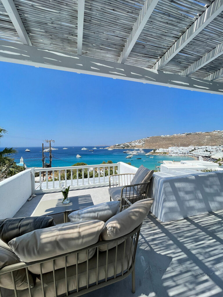 Outdoor furniture, white terrace, and amazing sea view in Mykonos' best rental home.
