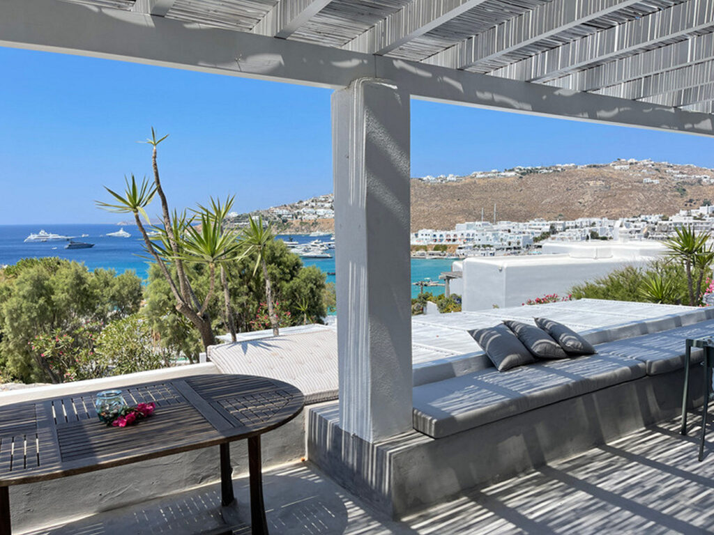 Cushions, a table, and a bench on a terrace in Mykonos best villas for booking.