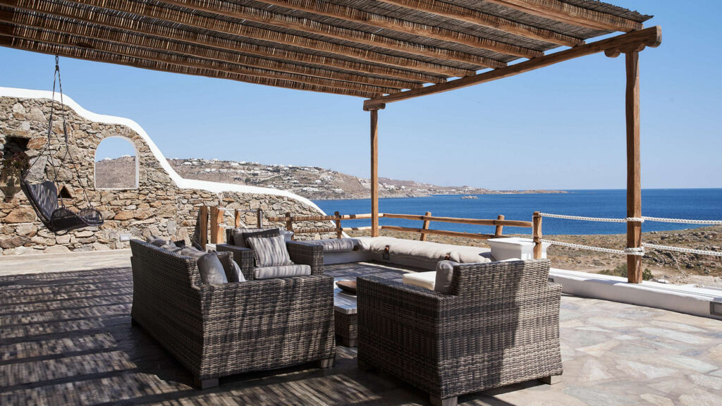 Comfy outdoor armchairs and a swing in Mykonos lavish villa for booking.