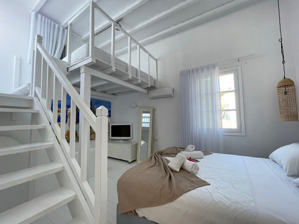 Bedroom with stairs and cozy bed in Mykonos top rental home.