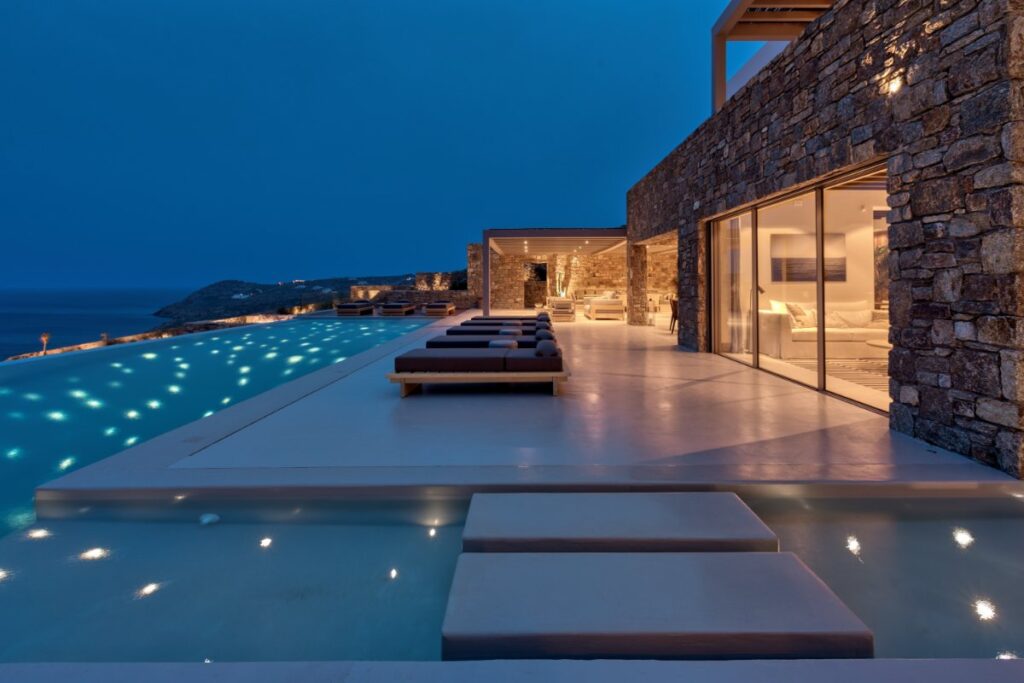 Adjusting lights, enjoyable atmosphere next to the swimming pool, and perfect sea view from Mykonos' best villa for rent.