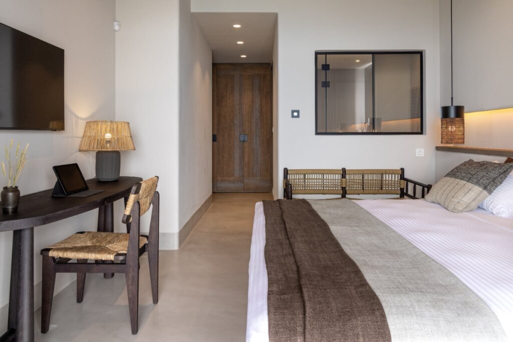 Cozy bed, wooden decoration, and amenities in a spacious bedroom in Mykonos holiday rental villa.