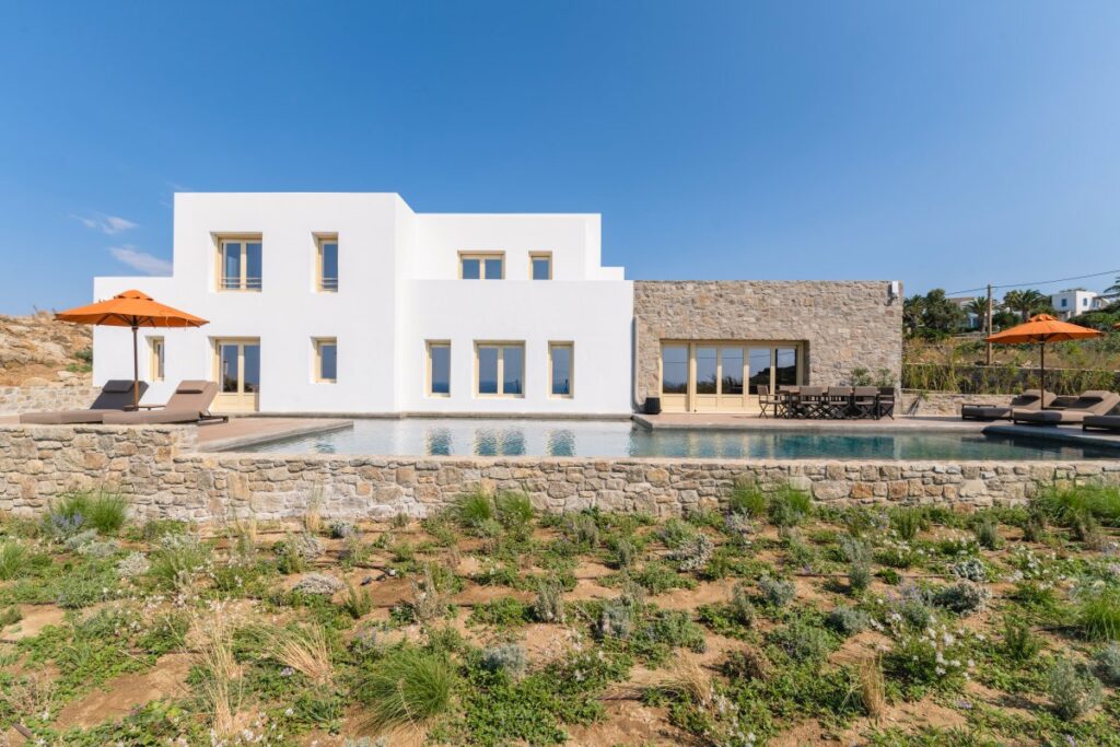 Mykonos white-colored and covered with natural stone cubes villa, ready for booking. Swimming pool and natural environment.