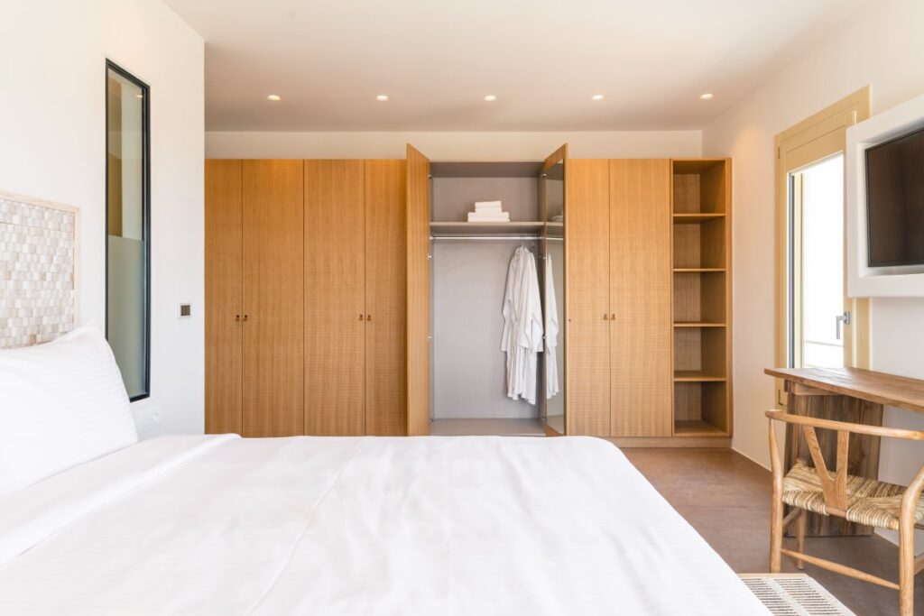 Spacious wooden wardrobes and a large bed in a luxurious Mykonos villa, ready for rent.