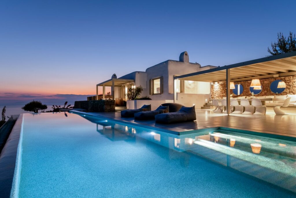 Glamorous infinity pool by the night, modern terrace in Mykonos exceptional villa ready for rent, Greece.