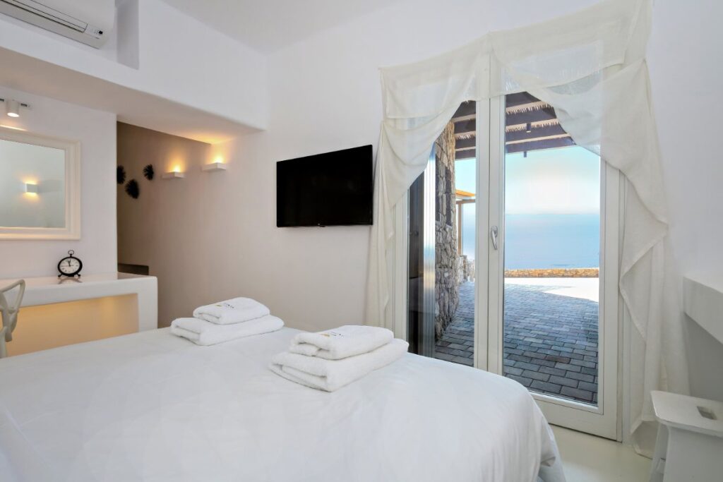 Comfortable beds in luxurious bedrooms with an impressive view of the sea from the best Mykonos villa, ready for rental.
