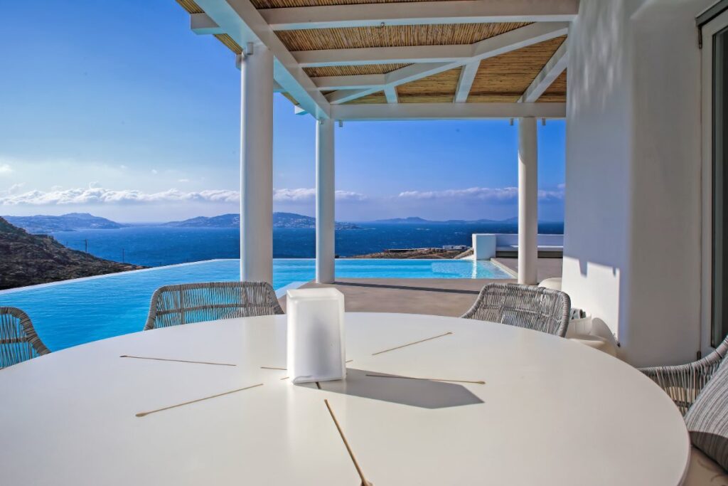 Outdoor dining table with astonishing blue water view from Mykonos top rental villa, Greece.
