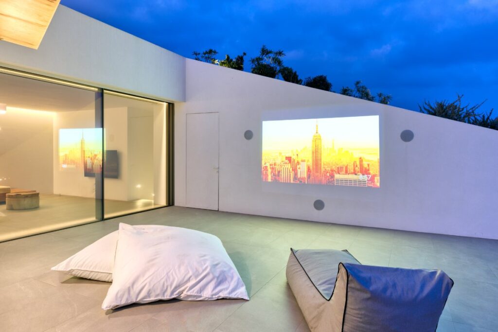 An outdoor cinema, comfy floor cushions on a terrace in Mykonos' top rental villa.