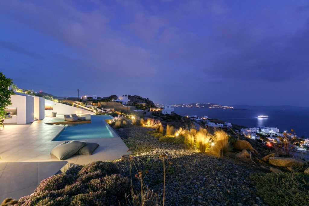 Relaxing outdoor oasis by the night. Sea view, swimming pool, and luxurious garden in Mykonos rental villa.